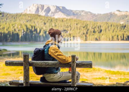 Uomo turistico sullo sfondo della vista panoramica mattina del Lago Nero Crno Jezero. Calma scena estiva del Parco Durmitor Nacionalni, località Zabljak Foto Stock