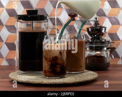 Preparazione di caffè freddo con latte in una French press, nota anche come cafetière, French press, o caffettiera a stantuffo Foto Stock