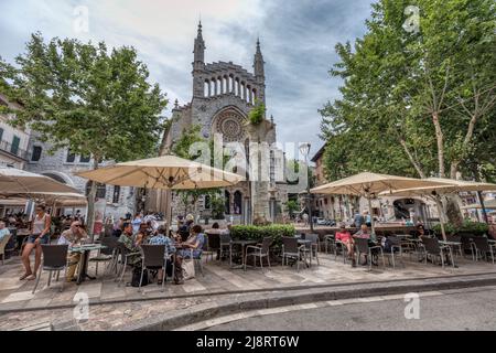 Persone ai caffè piazza principale Placa Constitucio in Soller di fronte alla chiesa di Sant Bartomeu, patrimonio mondiale dell'UNESCO Serra de Tramuntana montagne Foto Stock