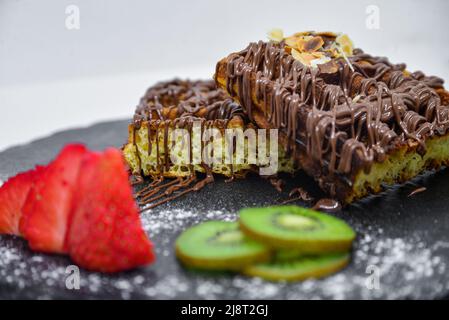 Un delizioso piatto di waffle con fragole e kiwi per guarnire Foto Stock