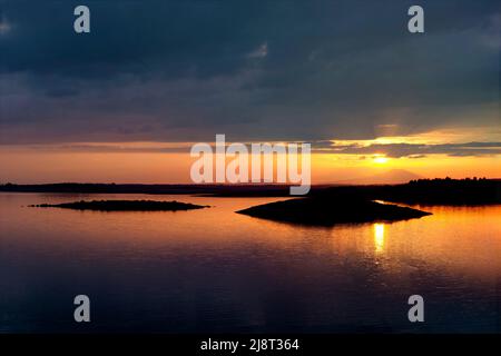 Cielo arancione nel serbatoio Gabriel y Galan, con piccole isole. Estremadura Foto Stock