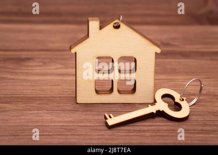 Forma di casa piatta e chiave di casa in legno. Acquisto di una casa prefabbricata. Foto Stock