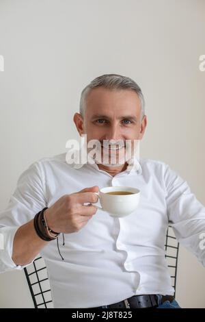 Fidato uomo d'affari che guarda a dio che ha il caffè del mattino in ufficio Foto Stock