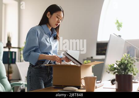 Triste donna asiatica imballaggio scatola sul posto di lavoro dopo essere stato licenziato Foto Stock
