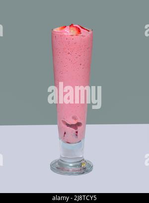 Bicchiere di succo di fragola con pezzi di fragola per decorazione su sfondo grigio Foto Stock