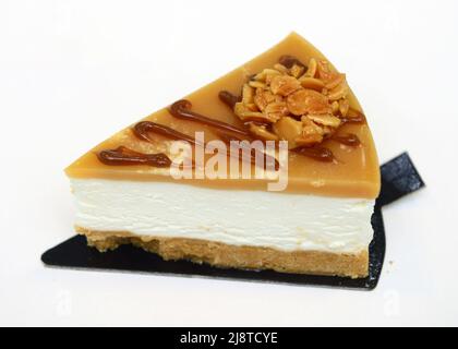 Fetta di cheesecake al caramello di pecan isolata su sfondo bianco Foto Stock