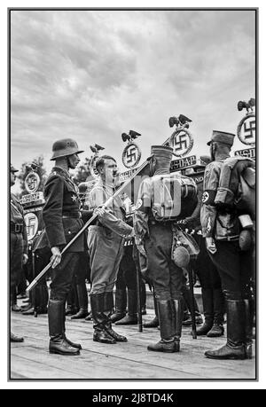 1930s Adolf Hitler in Sturmbleitung SA uniforme in un NSDAP Rally di Norimberga, incontrare i membri della Sturmbleitung SA; letteralmente 'Storm distaccamento') anche noto come le Camicie marroni, erano l'ala paramilitare originale del Partito nazista (Partito Nazionale Socialista Tedesco dei lavoratori). Ha giocato un ruolo significativo nell'ascesa al potere di Adolf Hitler nel 1920s e nel 1930s. I suoi scopi primari erano la protezione dei raduni e delle assemblee naziste. Foto Stock
