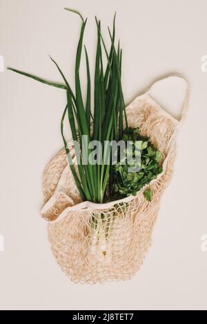 cipolle verdi fresche in borsa ecologica su sfondo bianco vista dall'alto, disposizione piatta. Alimenti biologici sani Foto Stock