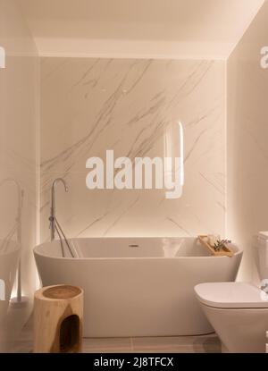 Bel bagno di lusso bianco e marmo carrara con vasca esentata e condotto come luce ambiente per rilassarsi con un design minimalista Foto Stock