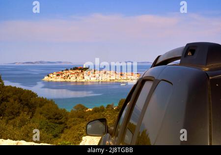 Impressioni di un viaggio su strada attraverso la Croazia con vista su un veicolo fuoristrada verso una piccola isola densamente costruita con case tradizionali negli Adriati Foto Stock