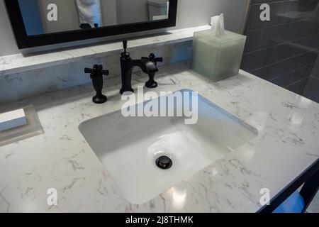 Focalizzazione angolata e selettiva su un moderno rubinetto nero per lavabo all'interno di un hotel di lusso di alto livello Foto Stock