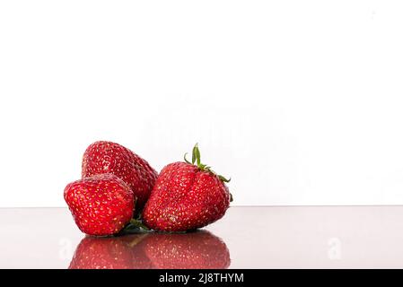 Fragole isolate. Fragola con foglia isolato. Tre fragole intere su bianco. Vista laterale. Naturale Foto Stock