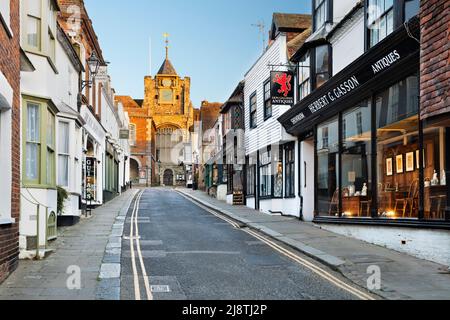 Negozi lungo Lion Street con la Chiesa di Santa Maria in luce del sole di sera, Rye, East Sussex, Inghilterra, Regno Unito, Europa Foto Stock