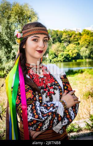 Una donna Ucraina in una camicia ricamata si erge sulla riva del fiume. Foto Stock