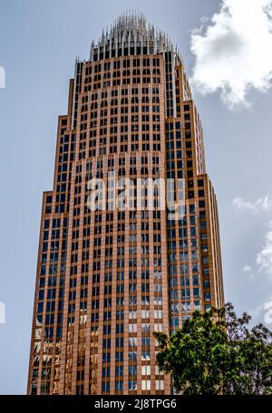 Esterno della sede centrale di Bank of America contro un cielo limpido con una nuvola luminosa, finestre, pavimenti e verde nel centro di Charlotte, NC. Foto Stock