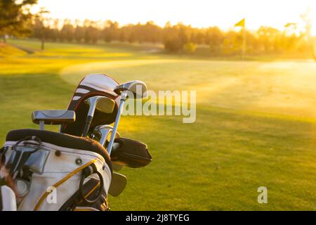 Golf club in borsa su paesaggio erboso contro cielo limpido al campo da golf durante il tramonto, spazio copia Foto Stock