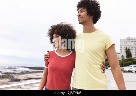 Sorridendo giovane afro americano coppia guardare lontano mentre in piedi contro il cielo, copia spazio Foto Stock