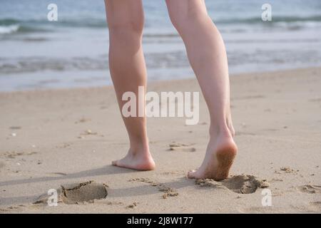 Gambe di una donna che cammina verso il mare Foto Stock