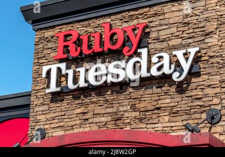 Esterno 'Ruby Tuesday' facciata marchio e logo per esterni in grassetto rosso e bianco lettere su sfondo di pietra in una luminosa giornata di sole. Foto Stock