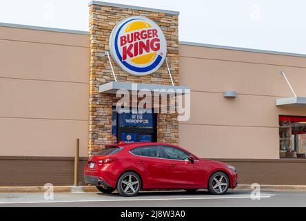 Outdoor, facciata di marca e logo per 'Burger King' alla sua finestra Drive Thru nella luce soffusa della mattina presto in una giornata di sole con un veicolo rosso. Foto Stock