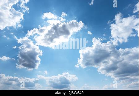 Sole raggi dietro le nuvole nel cielo blu. Tempo nuvoloso. Foto di alta qualità Foto Stock