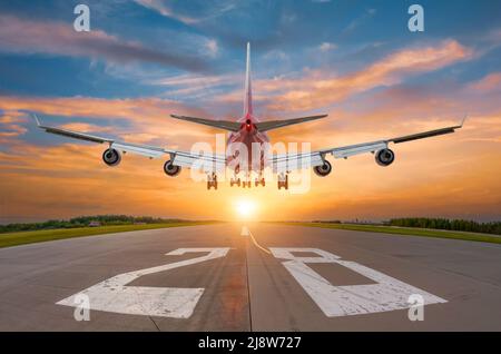 L'aereo atterra sulla pista durante l'alba, vista posteriore dalla fine della pista Foto Stock