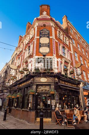 I clienti vestiti calorosamente seduti all'esterno del pub White Lion situato all'angolo tra James Street e Floral Street a Covent Garden, Londra. Foto Stock