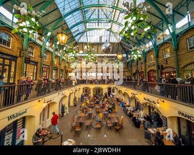 Zona pranzo seminterrato di Covent Garden decorata con grandi decorazioni natalizie vischio illuminate. Londra Foto Stock