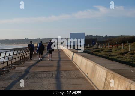 Jersey Channel Islands St Ouens Bay persone camminare lungo la passeggiata in serata con la Casa Bianca (le Don Hilton) sullo sfondo Foto Stock