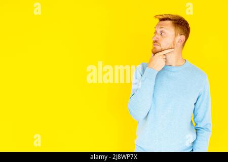 Il giovane uomo premuroso che osserva lo sfondo vuoto dello spazio della copia al lato Foto Stock