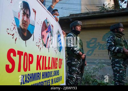 Le forze paramilitari indiane si levano in guardia mentre gli indù Kashmiri, localmente conosciuti come 'pandits' urlavano slogan durante la protesta a Budgam contro l'uccisione di Rahul Bhat, un dipendente del governo che è stato ucciso da sospettati ribelli all'interno del suo ufficio a Chadoora Budgam. Mentre le autorità indiane hanno assicurato alla comunità Kashmiri Pandit che tutti i lavori e le questioni relative alla sicurezza saranno risolti tra una settimana, la comunità richiede il trasferimento dalla regione del Kashmir il più presto possibile, dicendo che non possono rischiare la loro vita per lavoro. Foto Stock