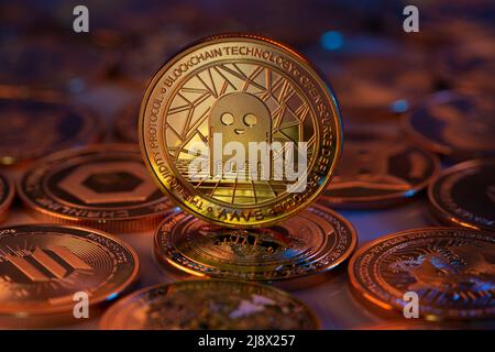 AAVE Cryptocurrency Coin fisico posto su cripto altcoins e illuminato con luci arancione e blu. Scatto macro. Messa a fuoco selettiva. Foto Stock