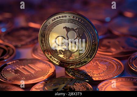 Ripple XRP Cryptocurrency Coin fisico posto su cripto altcoins e illuminato con luci arancione e blu nel Backgronde scuro. Scatto macro. Selettivo foc Foto Stock