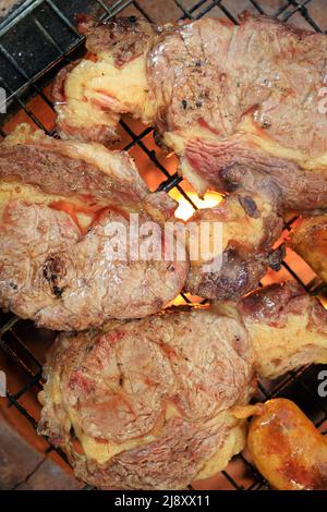 Primo piano grigliare la bistecca di carne sul grill del ferro sopra il fuoco. Cottura di un barbecue di carne Foto Stock