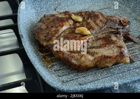 Pezzo di carne fritta con aglio in padella. Bistecca di carne alla griglia con aglio. Carne di maiale ben fatta Foto Stock
