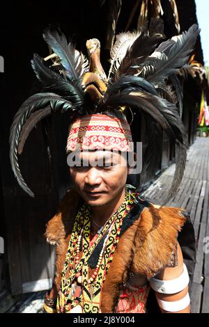 Un giovane uomo IBAN in guerriero headhunter regalia, tra cui hornbill feather headdress, al Sarawak Cultural Village vicino Kuching, Sarawak, Malesia. Foto Stock