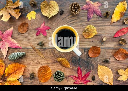 Sfondo autunnale con foglie autunnali su legno di quercia scuro con tazza di caffè nero. Vista dall'alto. Superficie piana. Foto Stock