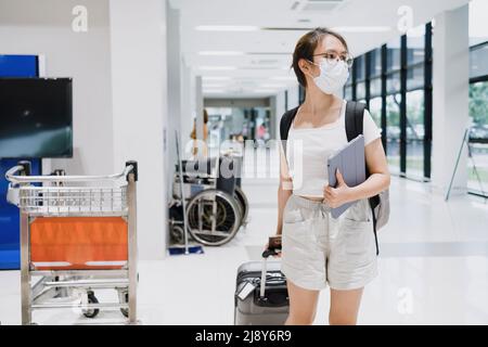 Turista asiatico femmina con tablet trascinare bagagli in aeroporto per viaggiare al di fuori del luogo, concetto di lavoro. Foto Stock