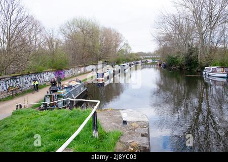 La gente sul percorso pedonali ciclabile e le narrowboats lungo il fiume Lea a Clapton in primavera Londra E5 Inghilterra Regno Unito Gran Bretagna KATHY DEWITT Foto Stock