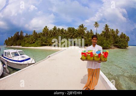 Il cameriere delle Maldive serve sul molo drink di benvenuto per i nuovi arrivi, l'isola delle maldive di Biyadhoo, l'atollo di South Male, le Maldive, l'Oceano Indiano, Asia Foto Stock