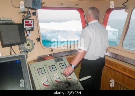 Dall'ala del ponte, il capitano dei 50 anni di Vittoria (50 Pobody Let) demolitore nucleare manovra la nave vicino ad un iceberg Foto Stock