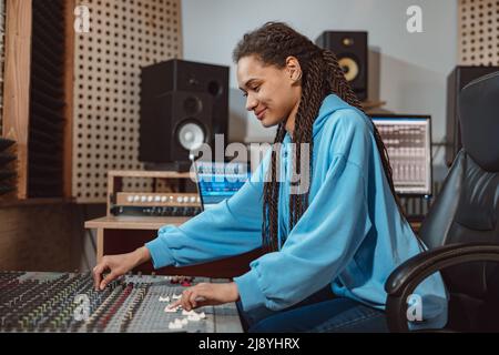 Elegante ingegnere audio femminile, produttore lavora in studio di registrazione musicale, utilizza mixer, software per creare canzoni cool Foto Stock