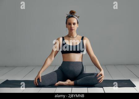 Donna incinta lo stiramento delle braccia e delle gambe, facendo allenamento prenatale a casa sul materassino yoga. Messa a fuoco selettiva Foto Stock