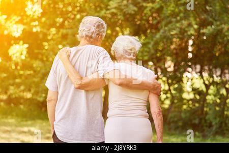 La coppia anziana innamorata va per una passeggiata nel giardino verde in estate Foto Stock