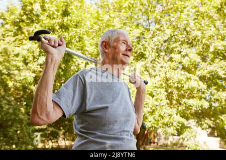 Uomo anziano vitale con la stampella in estate nel parco della clinica di riabilitazione Foto Stock