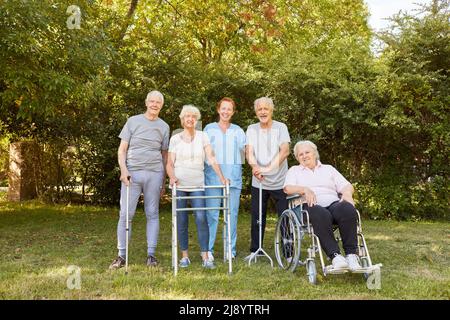 Fisioterapista e gruppo di anziani con disabilità in giardino in estate della clinica di riabilitazione Foto Stock