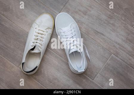 Coppia di scarpe alla moda bianche vecchie e nuove su sfondo di legno chiaro, vista dall'alto. Foto di alta qualità Foto Stock