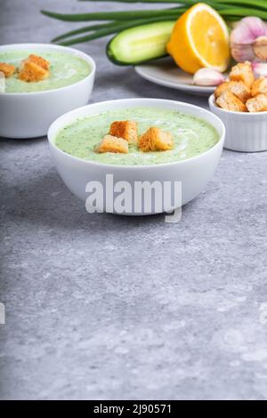 Zuppa fredda di panna vegana con cetriolo, yogurt, aglio, erbe aromatiche, limone e crostini. Concetto di alimento di dieta. Cibo vegetariano e vegano Foto Stock