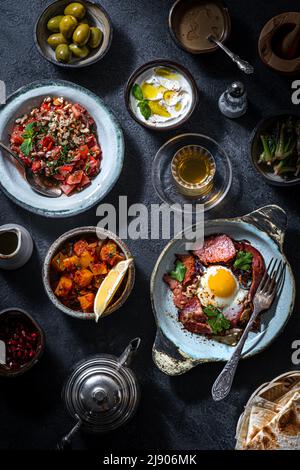 Tavolo per la colazione turco. Dolci piatti, verdure, verdure, olive, formaggi, uova fritte, spezie, marmellate, miele, tè in pentola di rame e tulipani bicchieri Foto Stock