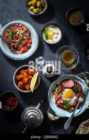 Tavolo per la colazione turco. Dolci piatti, verdure, verdure, olive, formaggi, uova fritte, spezie, marmellate, miele, tè in pentola di rame e tulipani bicchieri Foto Stock